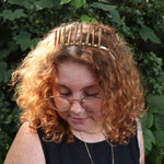 A woman wearing the Fairy Crown / Celtic Tiara - Gold Coral in front of greenery.