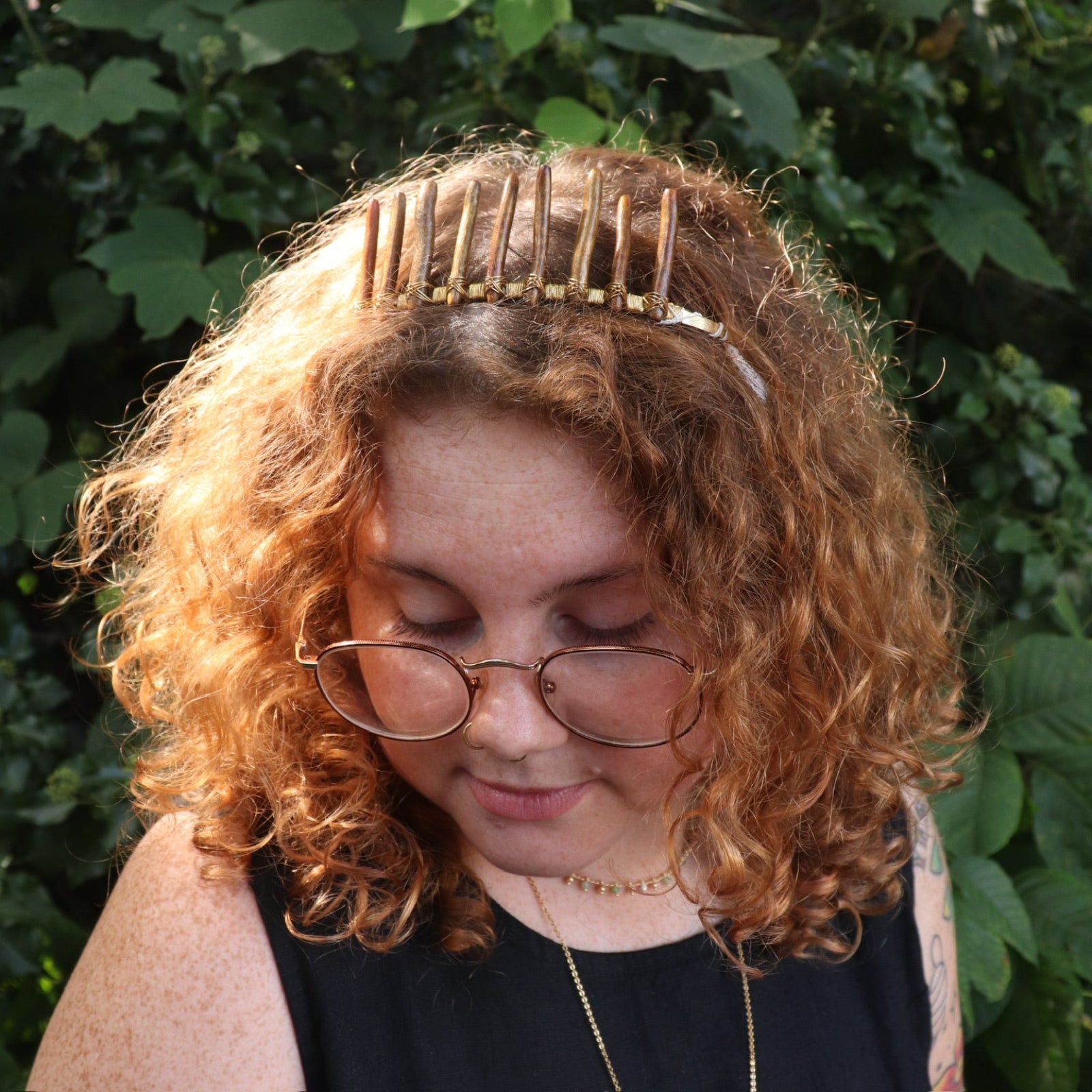 A woman wearing the Fairy Crown / Celtic Tiara - Gold Coral in front of greenery.