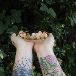 Someone holding the Fairy Crown / Celtic Tiara - Peruvian Yellow Opal in front of greenery.