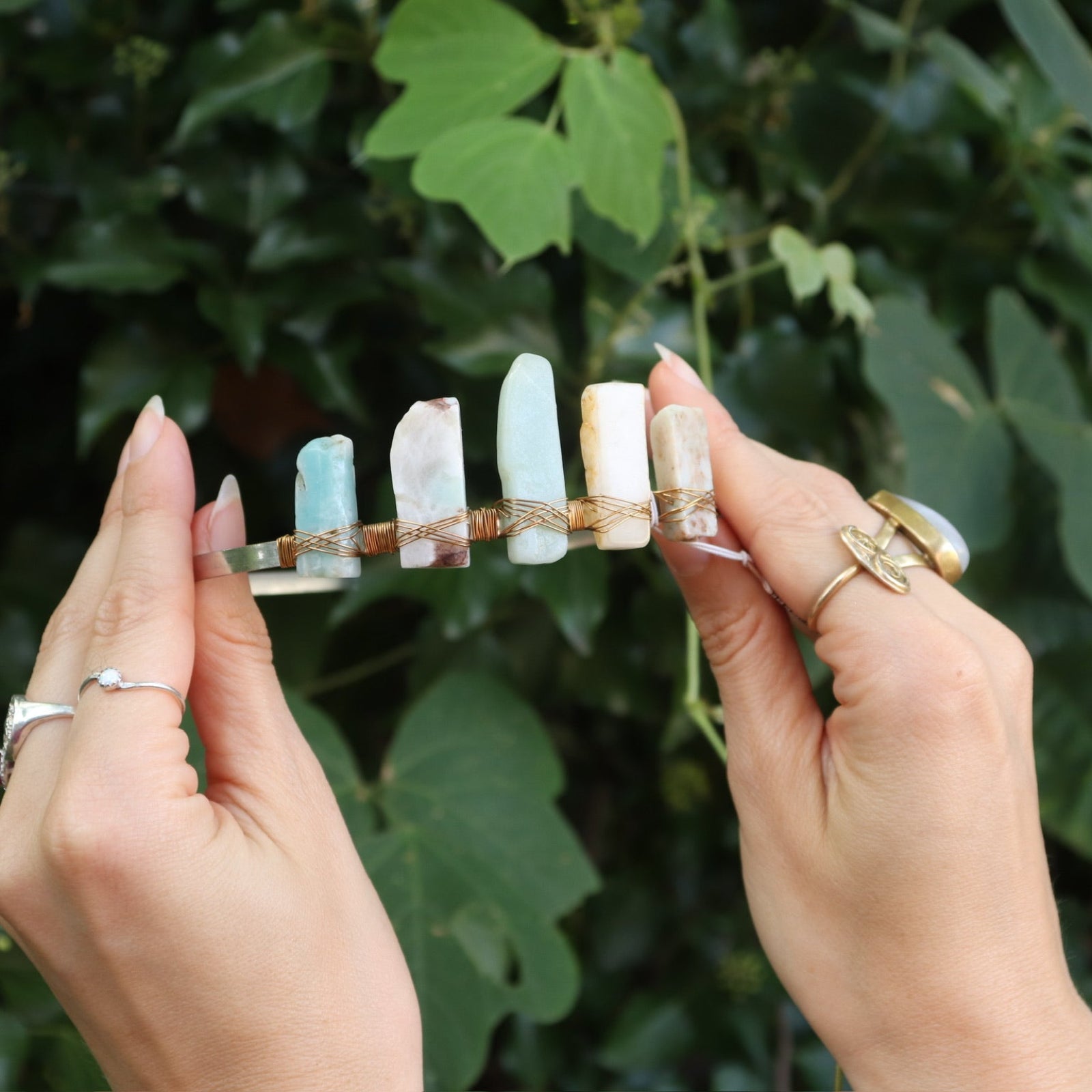 Someone holding the Gemstone Tiara / Crown - Amazonite in front of the greenery.