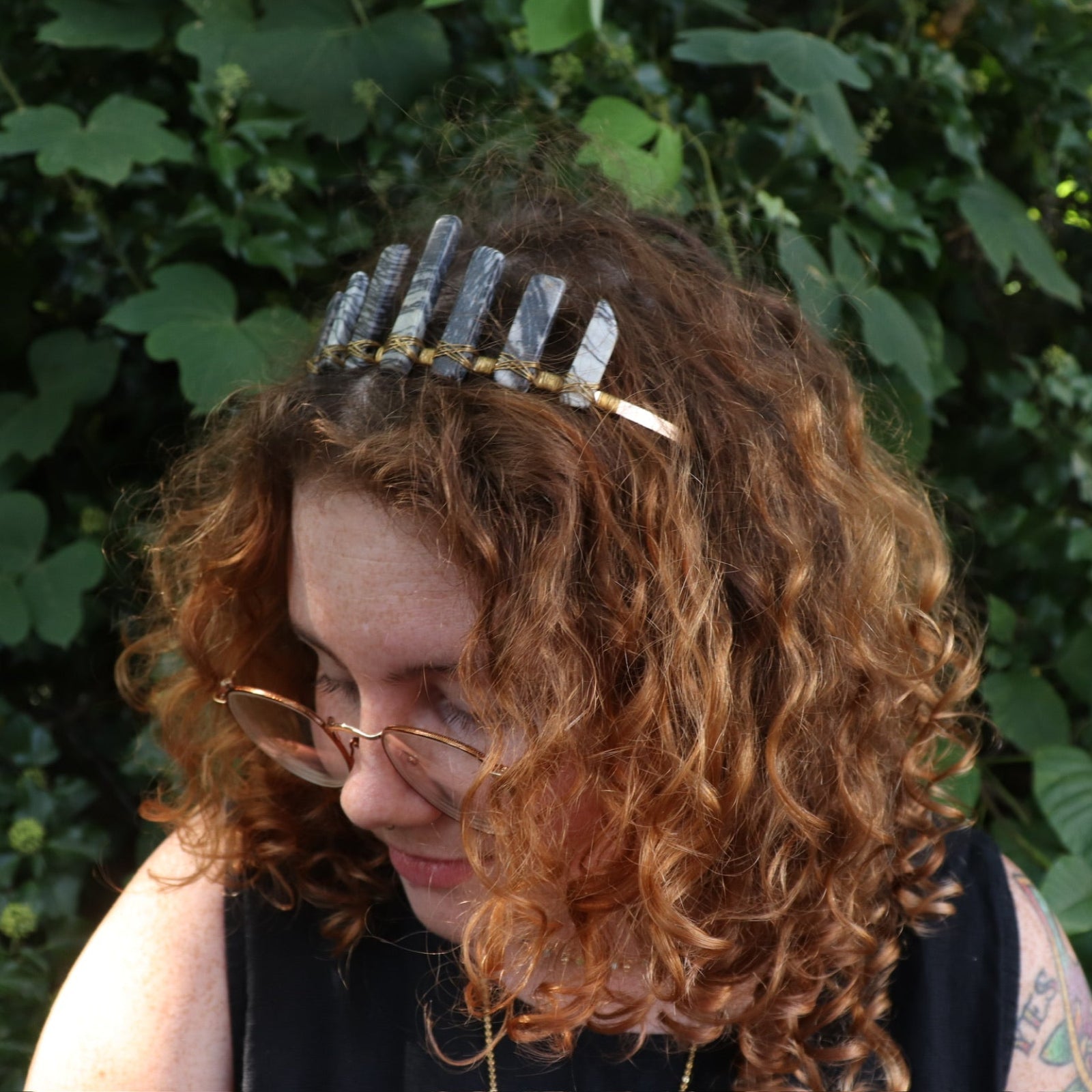 A woman wearing the Fairy Crown / Celtic Tiara - Black Line Jasper - Spiderweb in front of greenery.