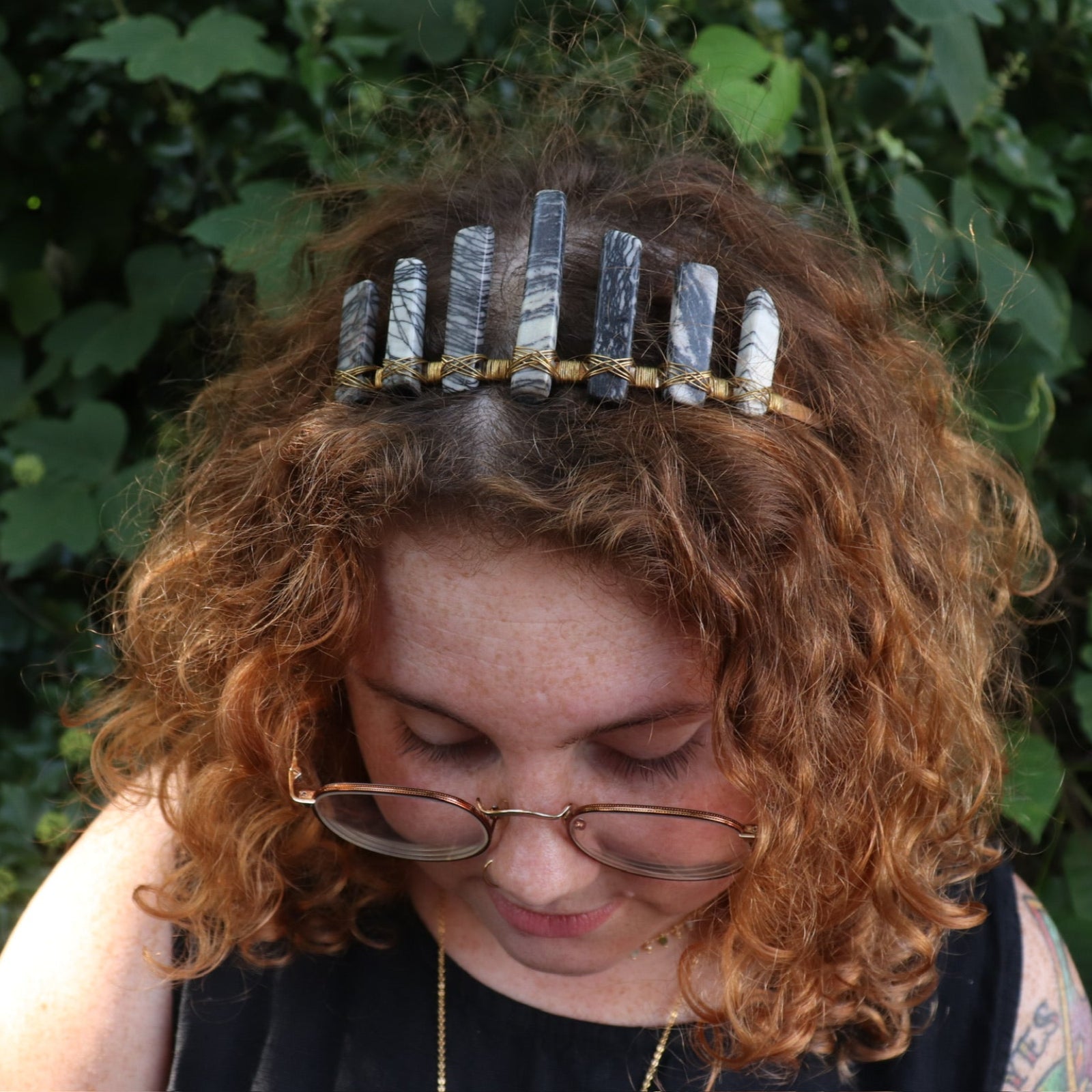 A woman wearing the Fairy Crown / Celtic Tiara - Black Line Jasper - Spiderweb in front of greenery.