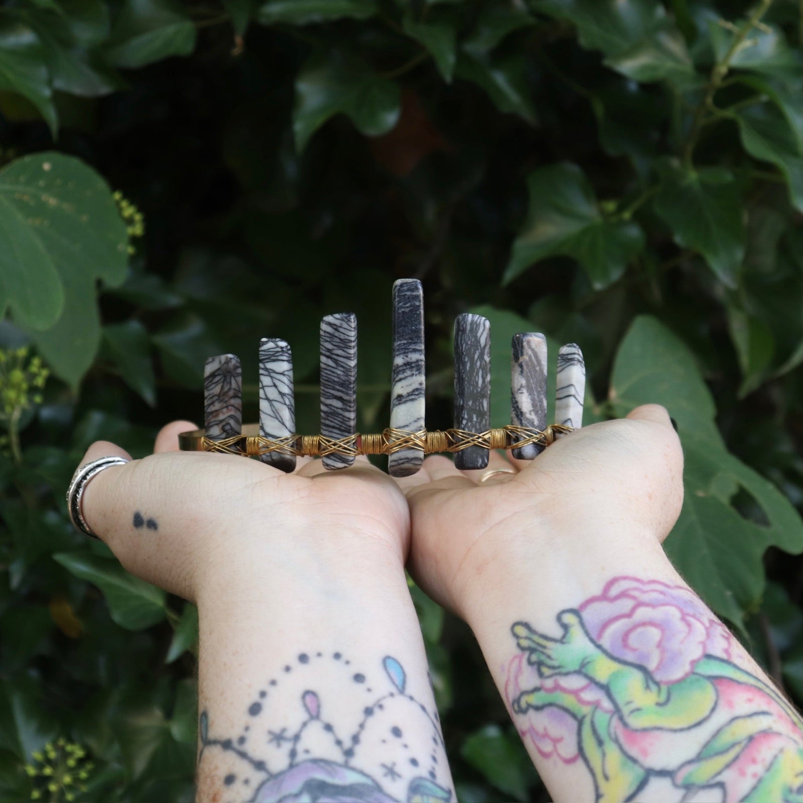 Someone holding the Fairy Crown / Celtic Tiara - Black Line Jasper - Spiderweb in front of greenery.