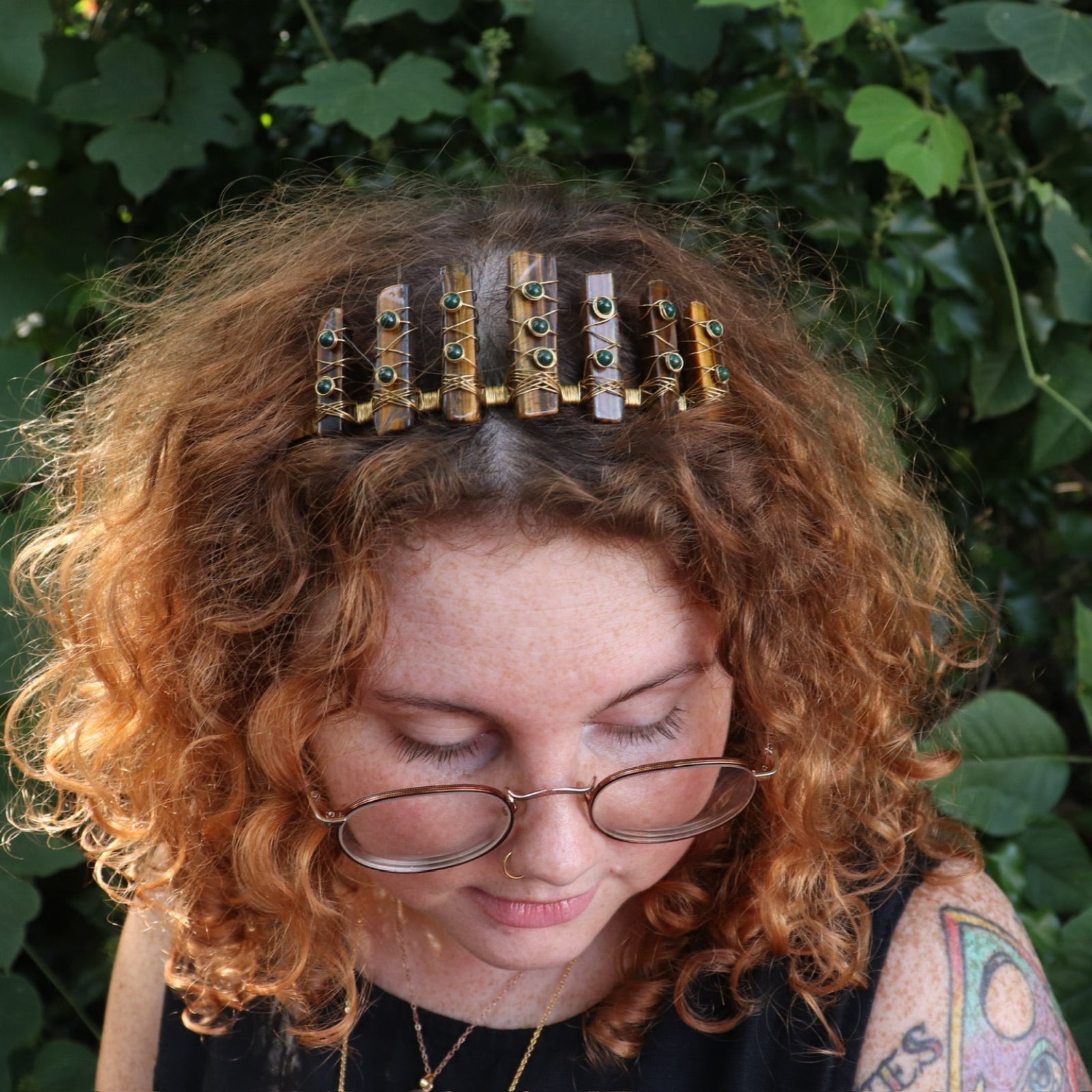 A woman wearing the Tigers Eye & Malachite Tiara in front of greenery.