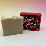 The Yuletide Glow Holiday Bar Soap in front of a pink and yellow background.