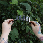 Someone holding the Fairy Crown / Celtic Tiara - Black Labradorite / Larvikite in front of greenery.