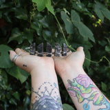 Someone holding the Fairy Crown / Celtic Tiara - Black Labradorite / Larvikite in front of greenery.