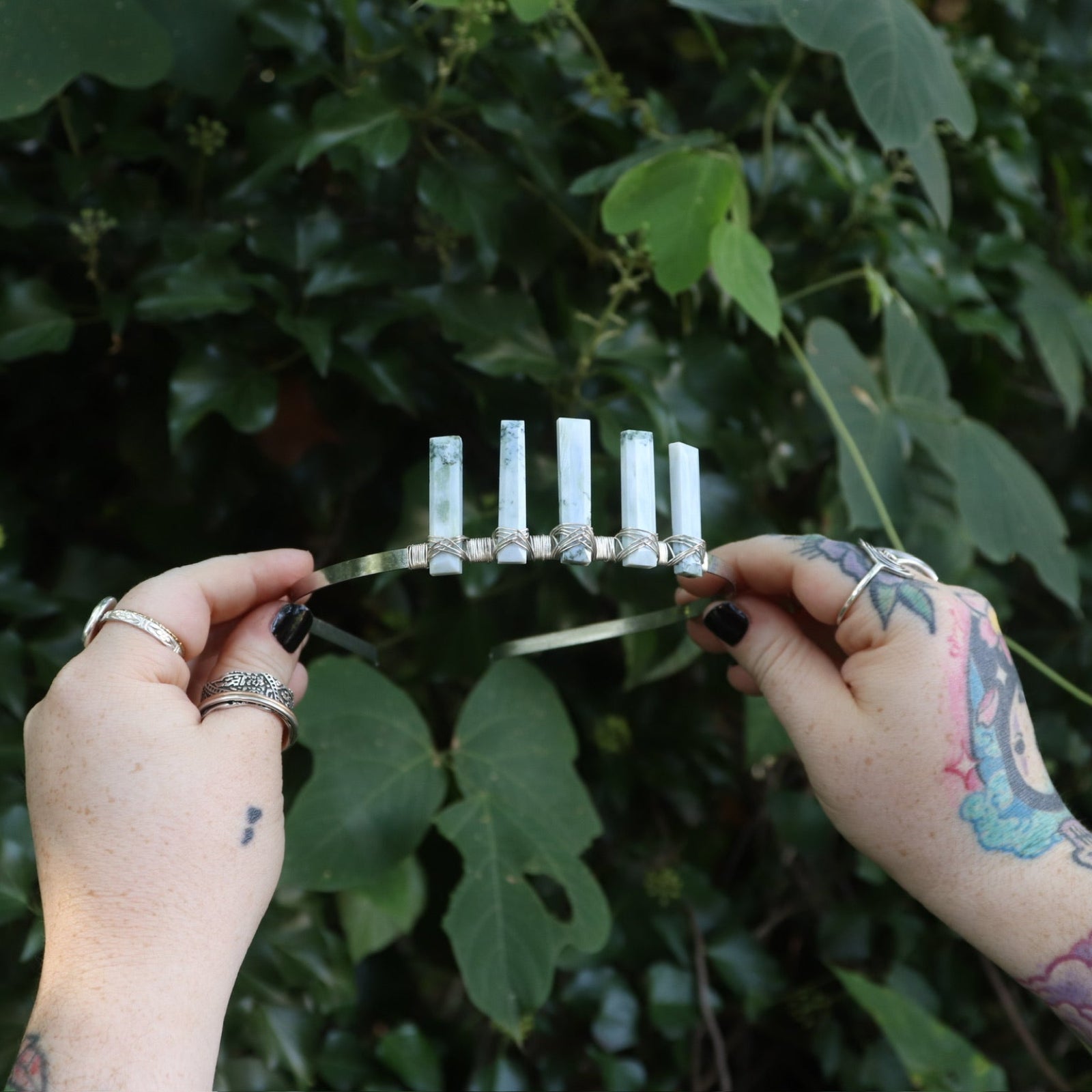 Someone holding the Fairy Crown / Celtic Tiara - Oregon Blue Opal in front of greenery.