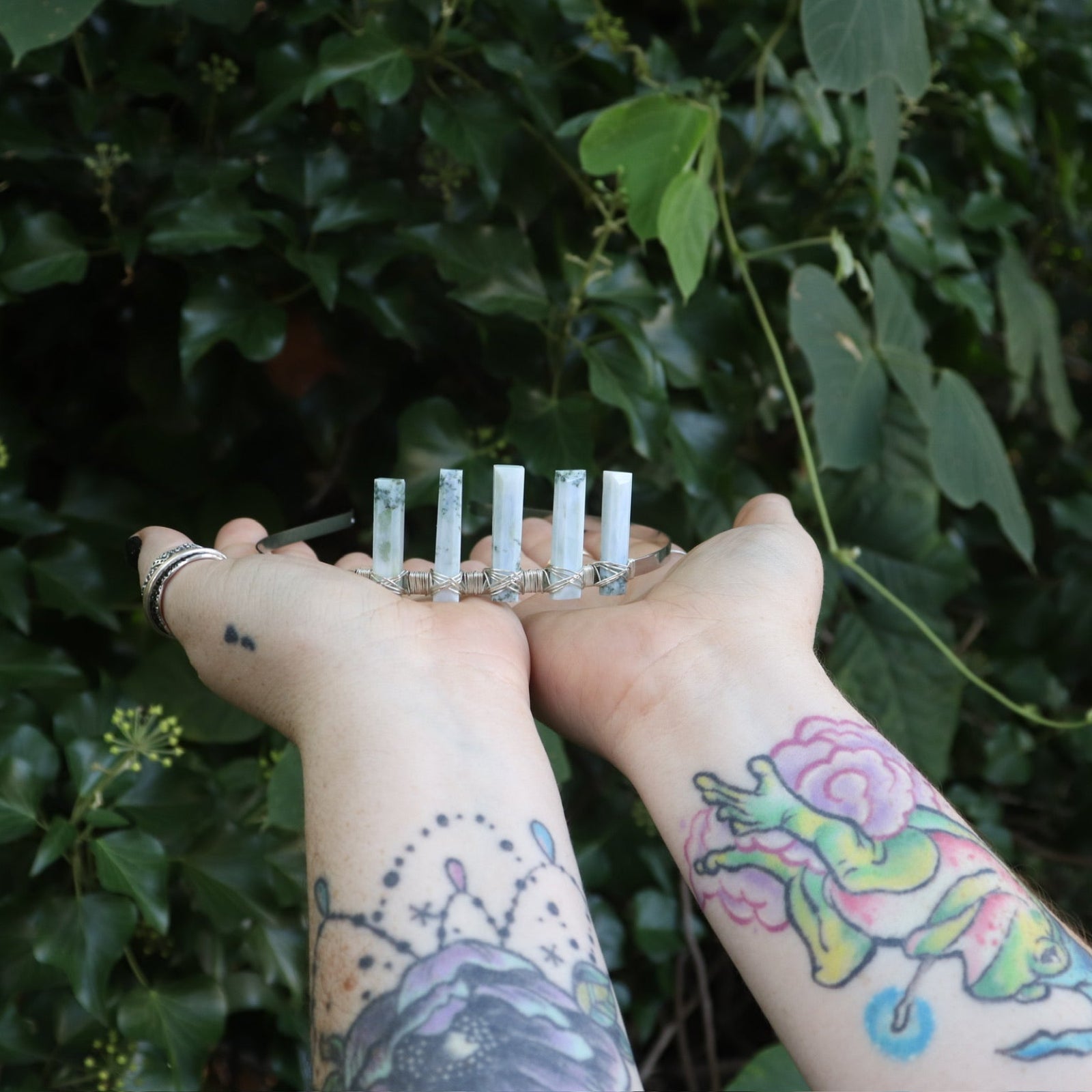 Someone holding the Fairy Crown / Celtic Tiara - Oregon Blue Opal in front of greenery.