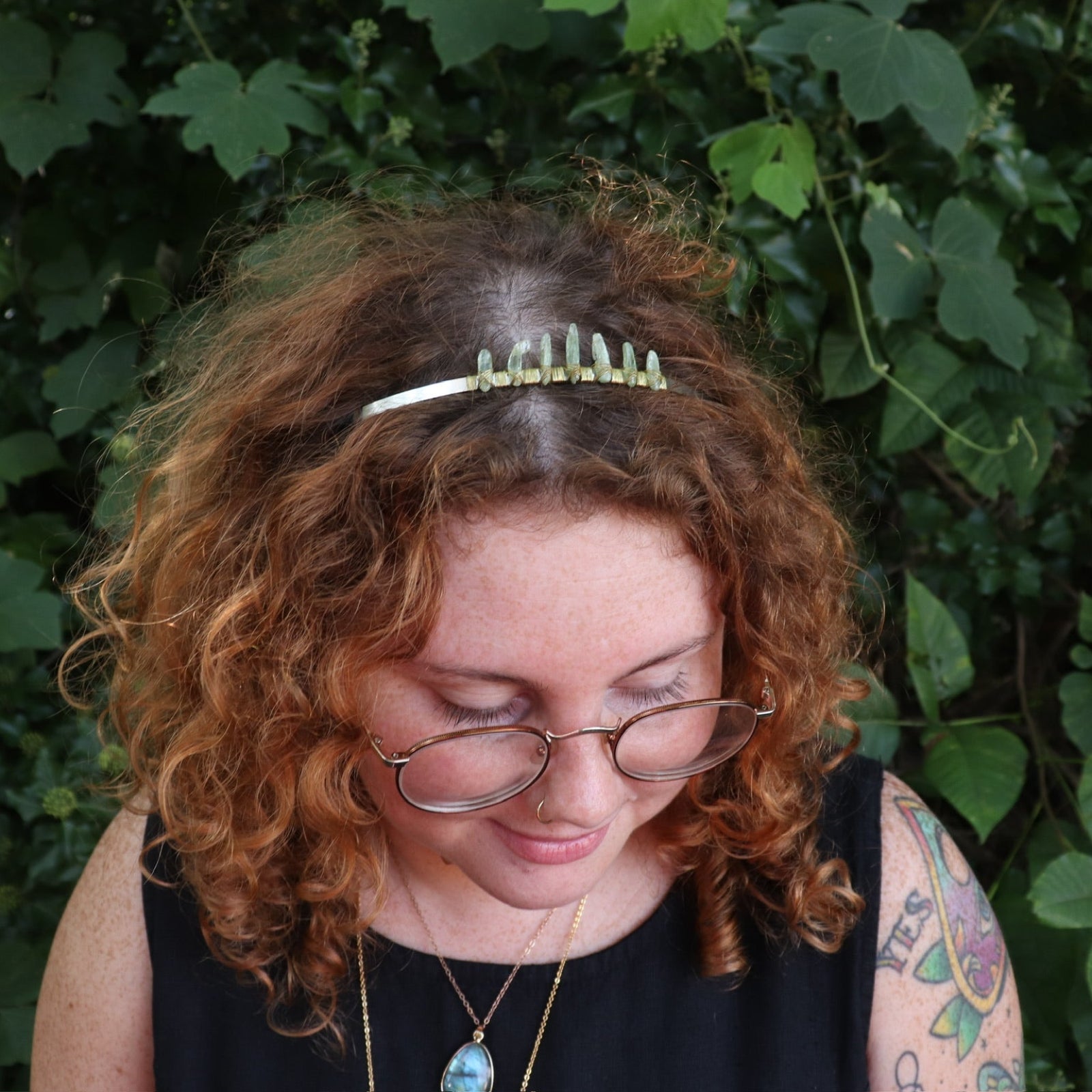 A woman wearing the Fairy Crown / Celtic Tiara - Green Kyanite in front of greenery.