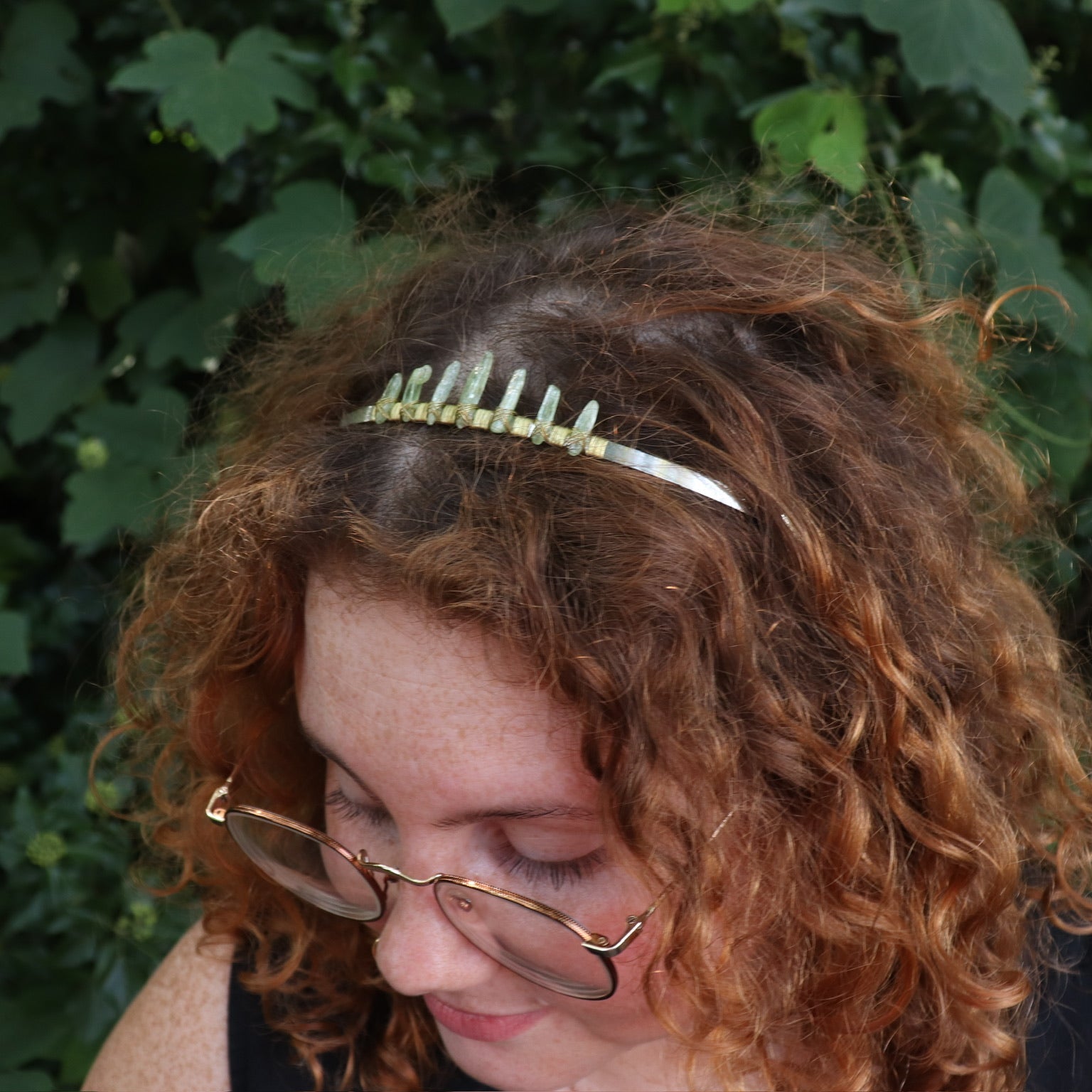 A woman wearing the Fairy Crown / Celtic Tiara - Green Kyanite in front of greenery.