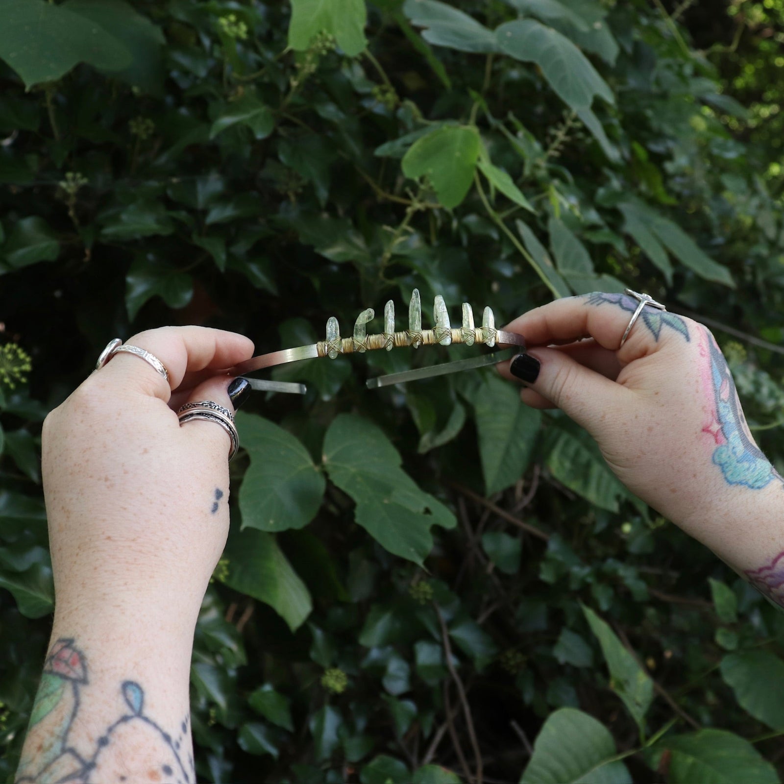 Someone holding the Fairy Crown / Celtic Tiara - Green Kyanite in front of greenery.