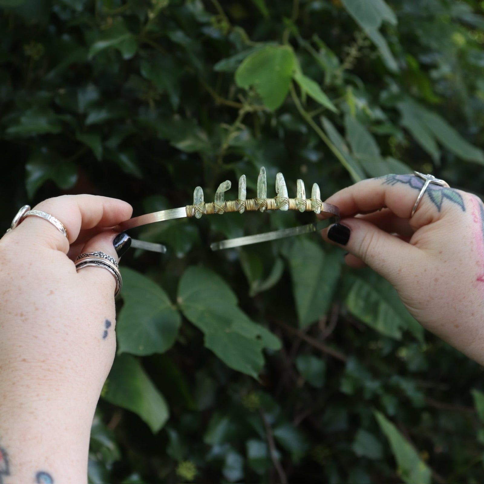 Someone holding the Fairy Crown / Celtic Tiara - Green Kyanite in front of greenery.