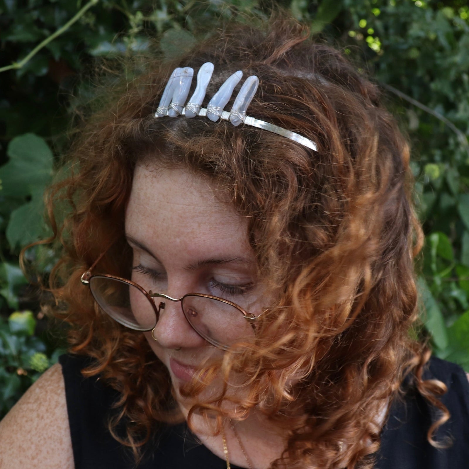 A woman wearing the Fairy Crown / Celtic Tiara - Blue Chalcedony in front of greenery.