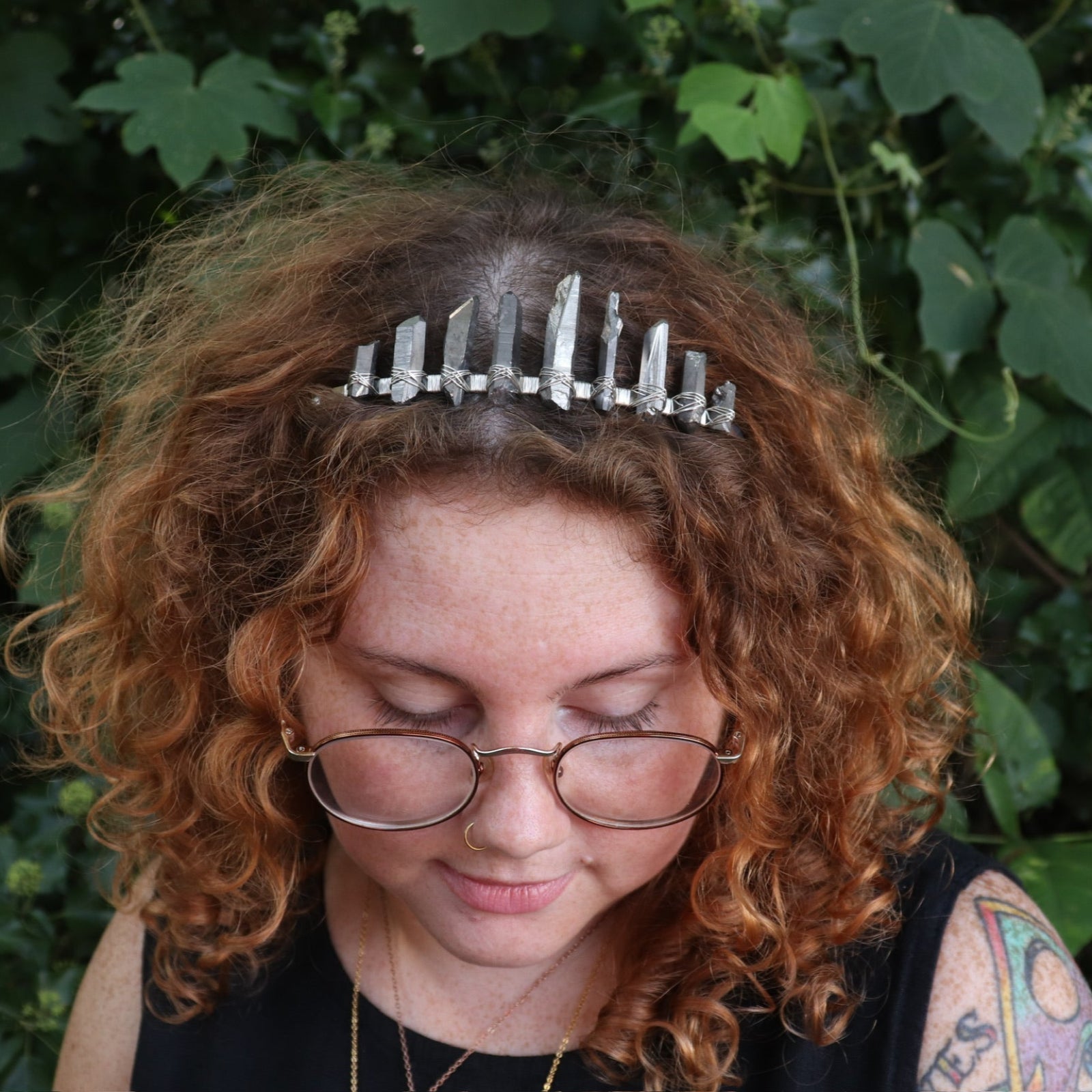 A woman wearing the Fairy Crown / Celtic Tiara - Titanium Quartz in front of greenery.
