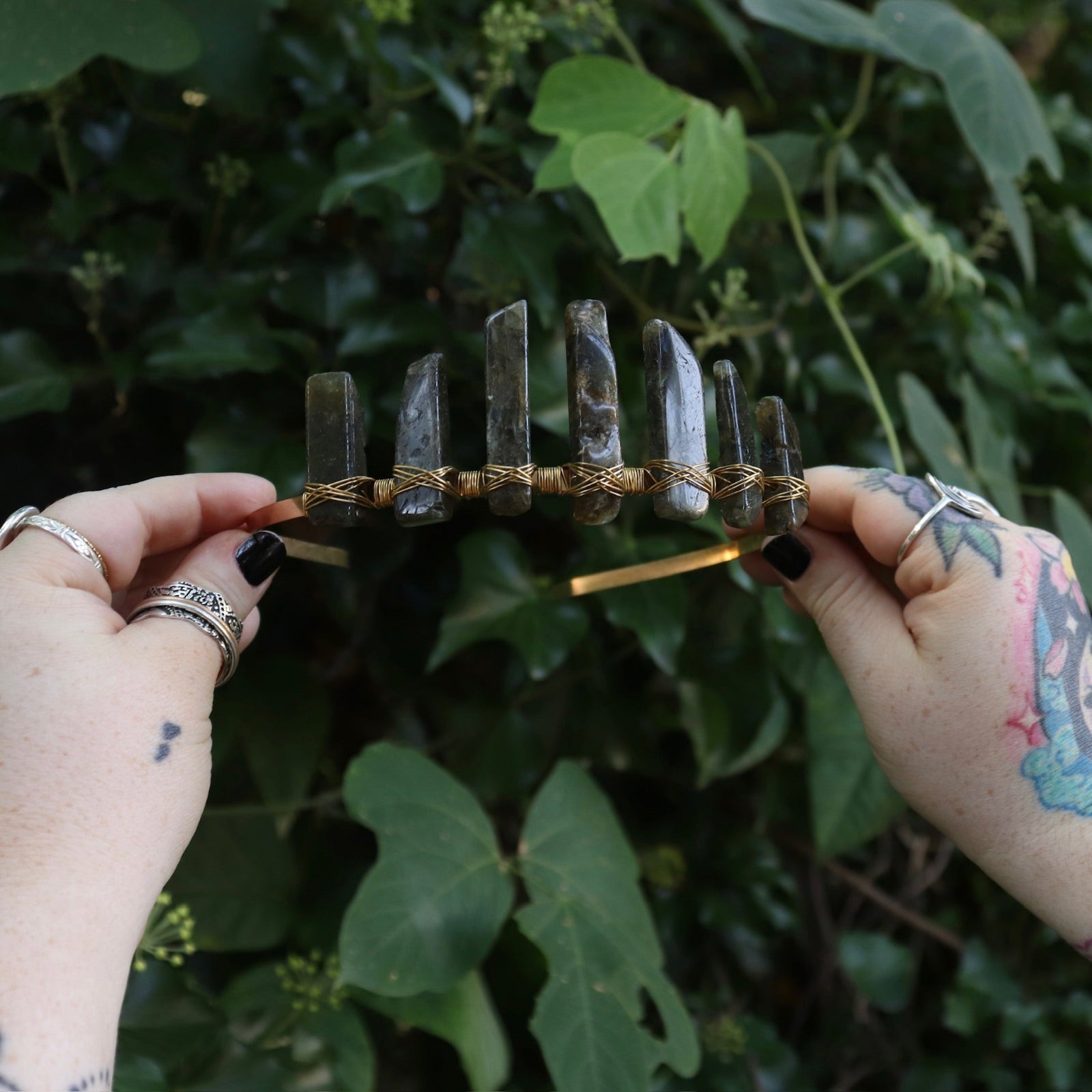 Someone holding the Fairy Crown / Celtic Tiara - Labradorite in front of greenery.