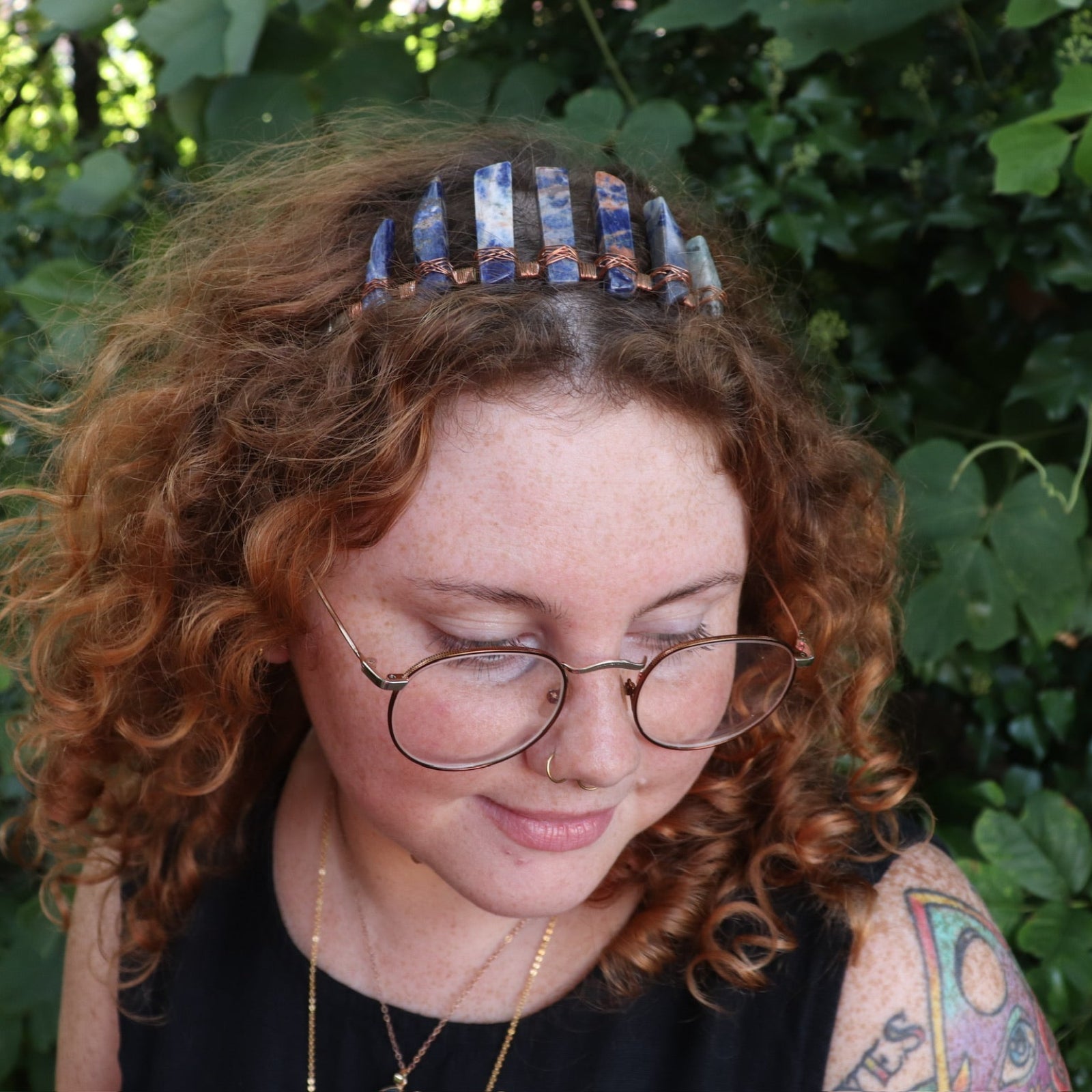 A woman wearing the Fairy Crown / Celtic Tiara - Orange & Blue Sodalite in front of greenery.