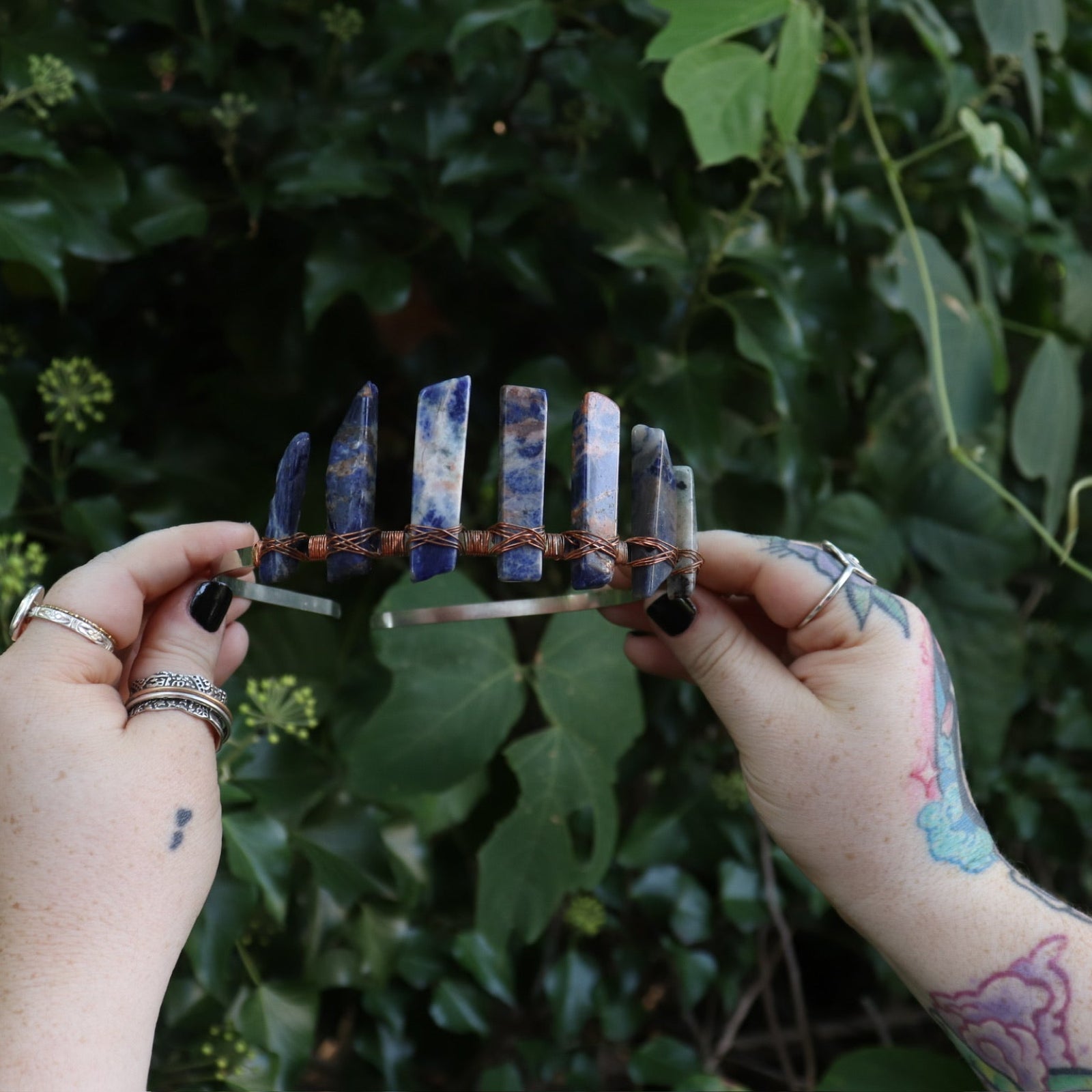 Someone holding the Fairy Crown / Celtic Tiara - Orange & Blue Sodalite in front of greenery.