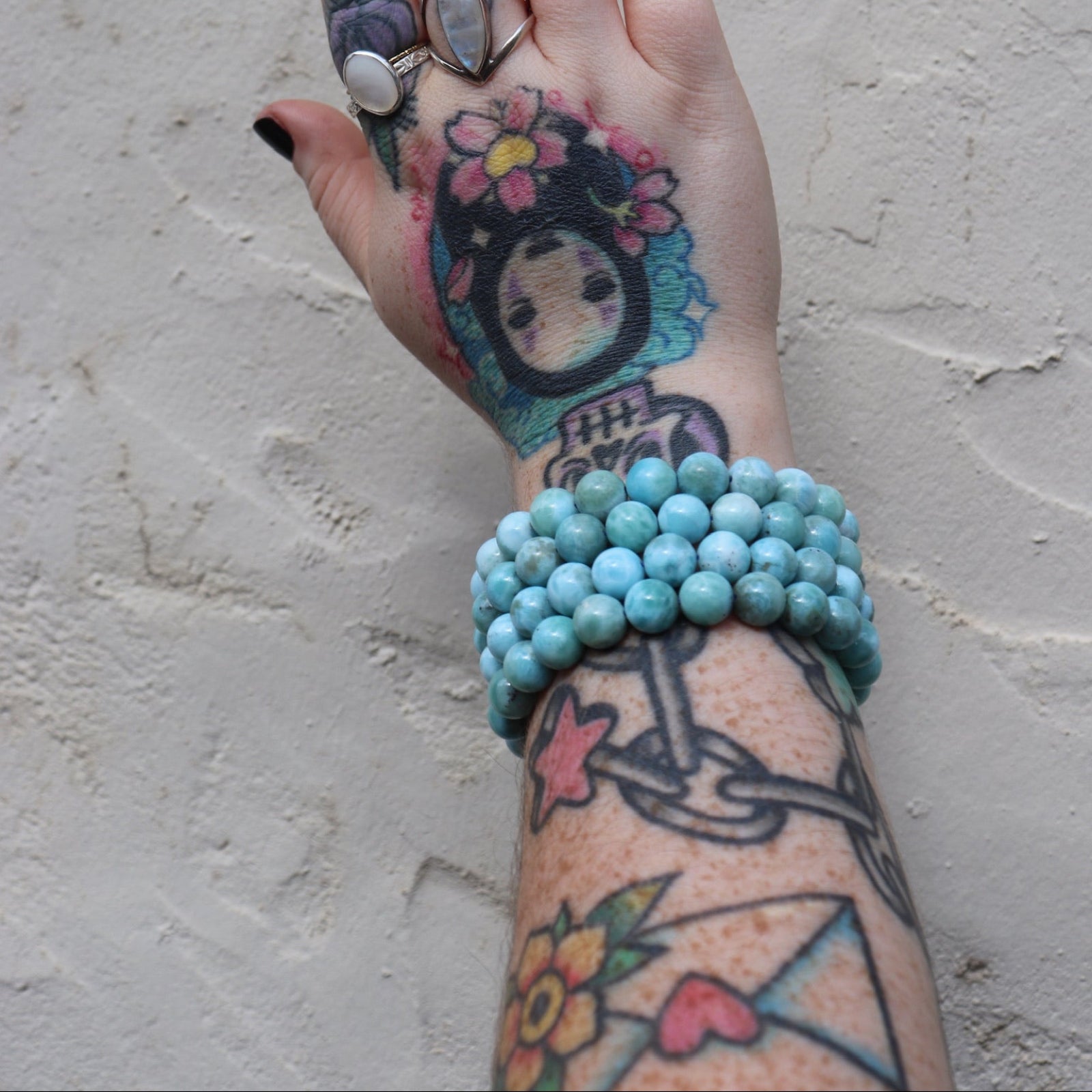 Someone wearing three of the large Natural Larimar Bracelet – 7.5” Stretch Fit.