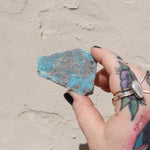 Someone holding a Larimar Crystal Slab in front of a white wall.
