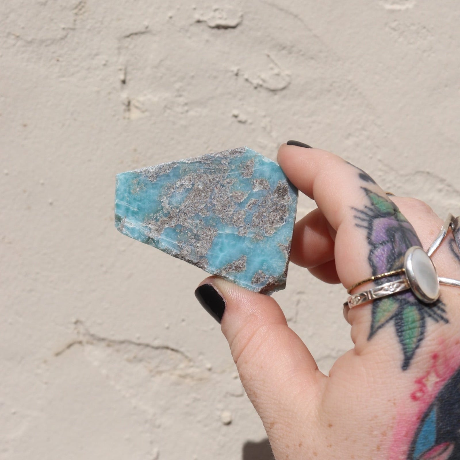 Someone holding a Larimar Crystal Slab in front of a white wall.