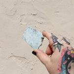 Someone holding a Larimar Crystal Slab in front of a white wall.