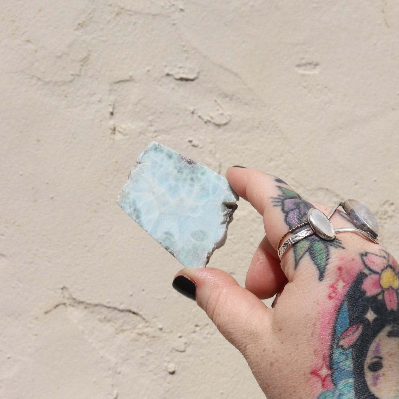 Someone holding a Larimar Crystal Slab in front of a white wall.