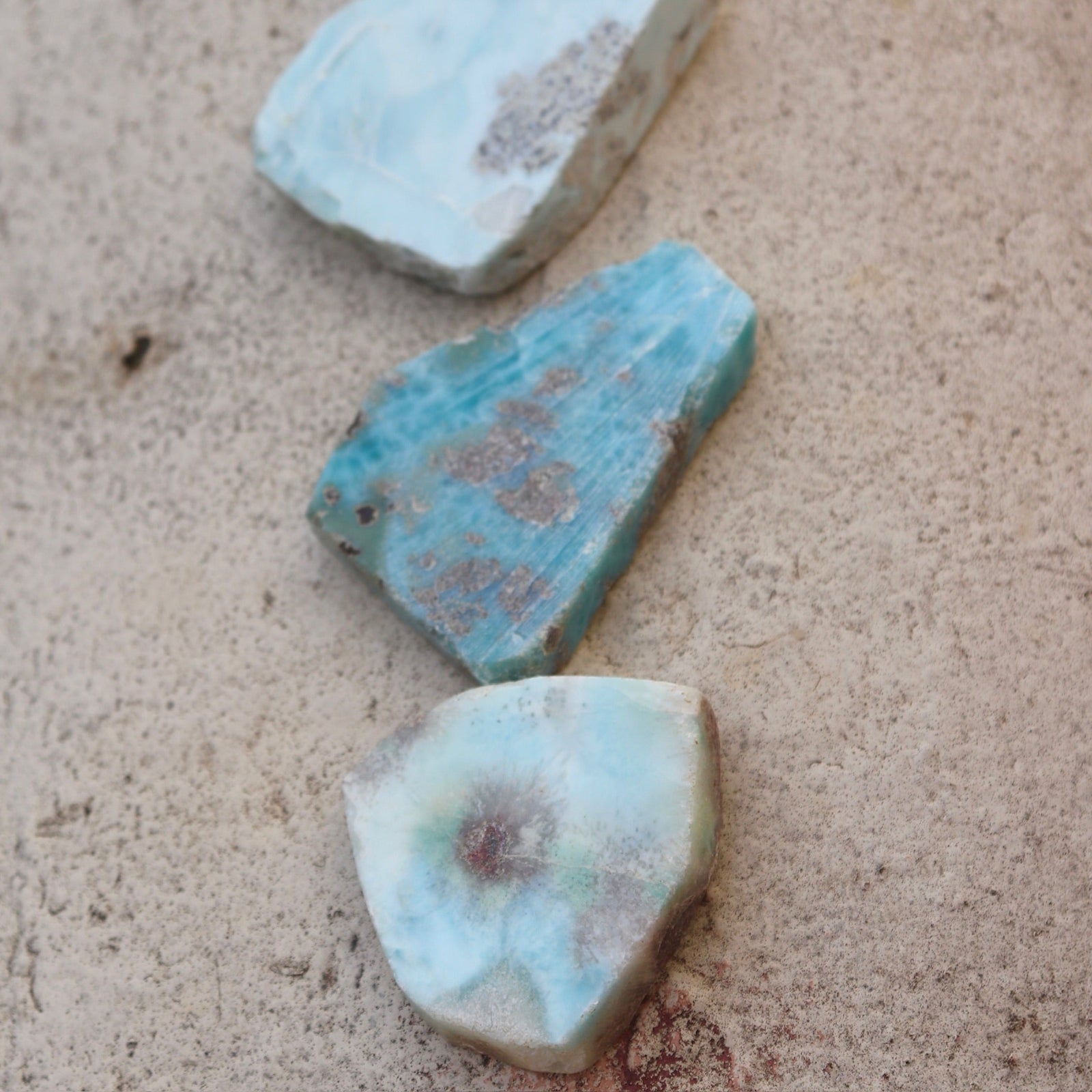 Some Natural Larimar Crystal Slabs on a cement background.