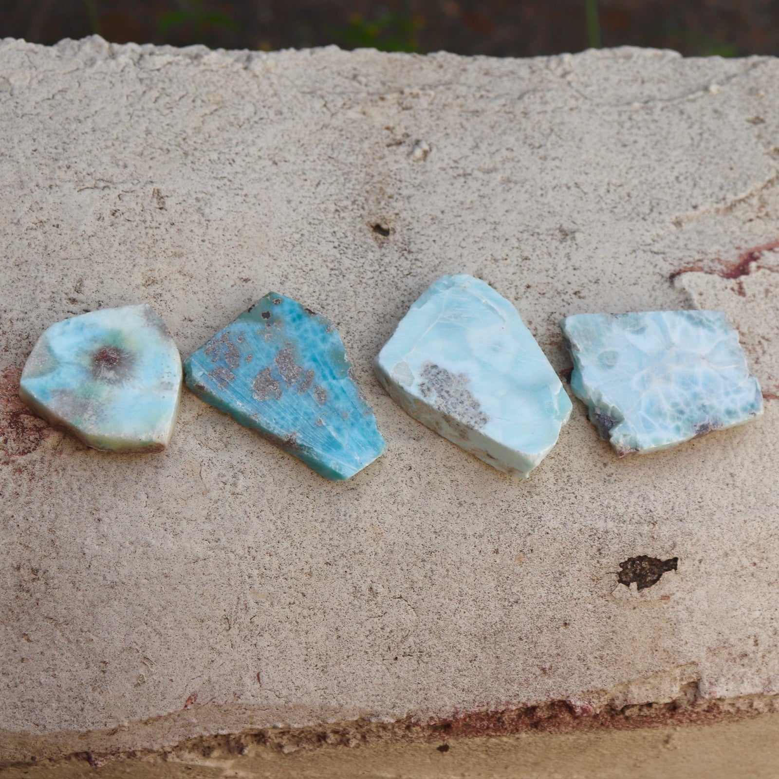 Some Natural Larimar Crystal Slabs on a cement background.