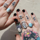 Someone wearing three of the Natural Larimar Stainless Steel Rings in front of a white wall.