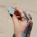 Someone holding a Natural Larimar Small Crystal Slab in front of a white wall.
