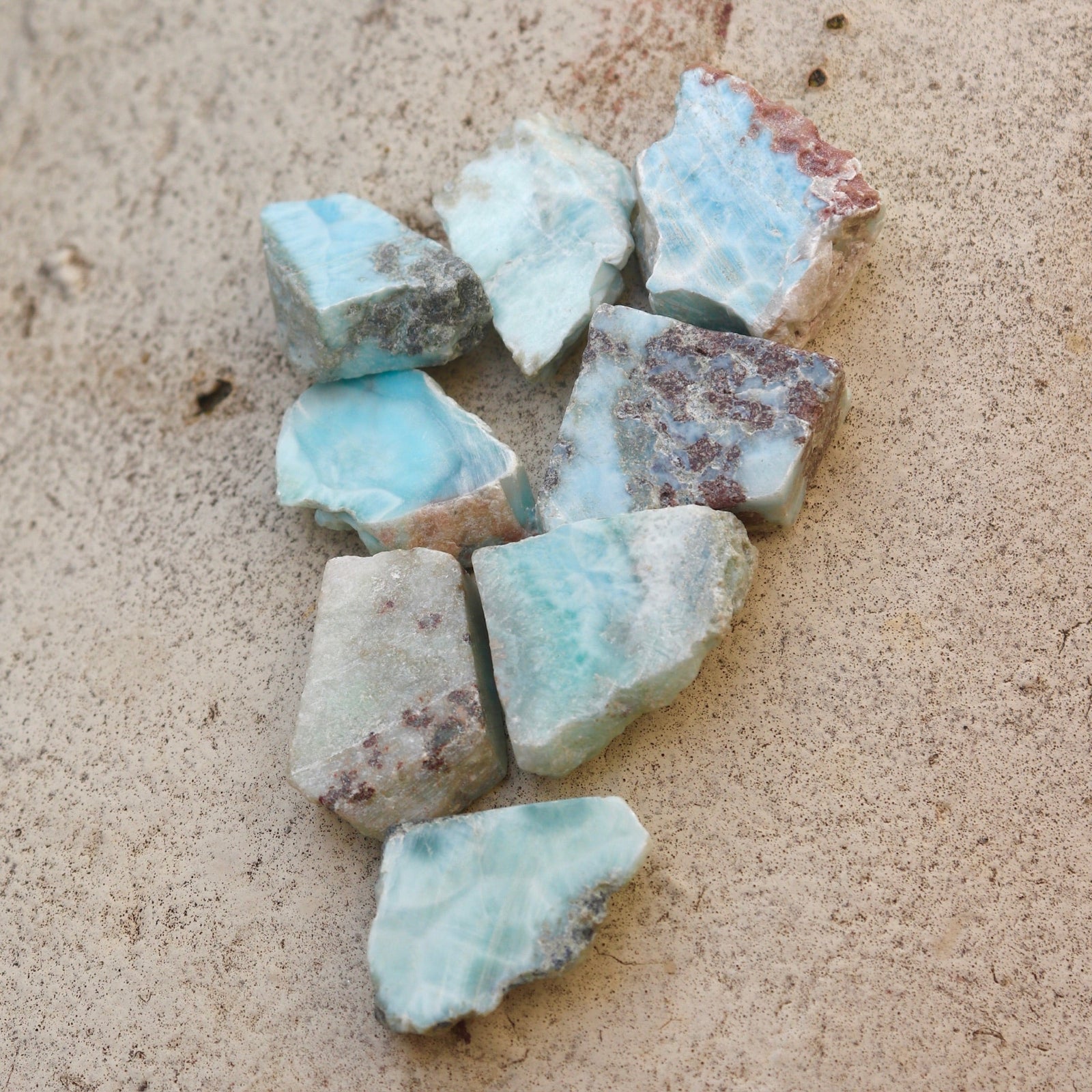 Multiple Natural Larimar Small Crystal Slabs on a cement background.