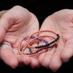 Someone holding all the crystal faceted beads + Copper Bracelets.