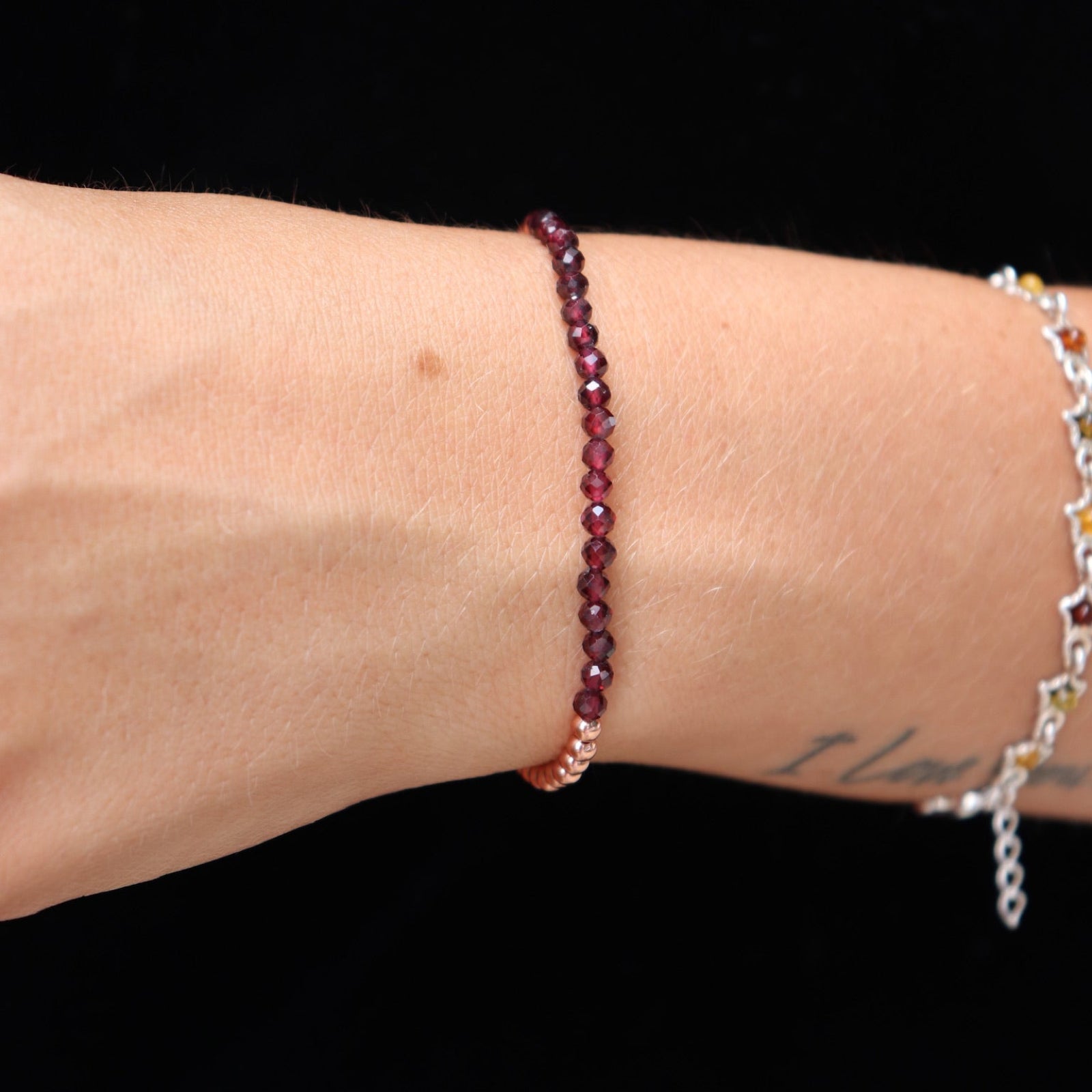 Someone wearing the Dainty and Elegant Multi-Faceted Garnet Beads + Copper Bracelet.