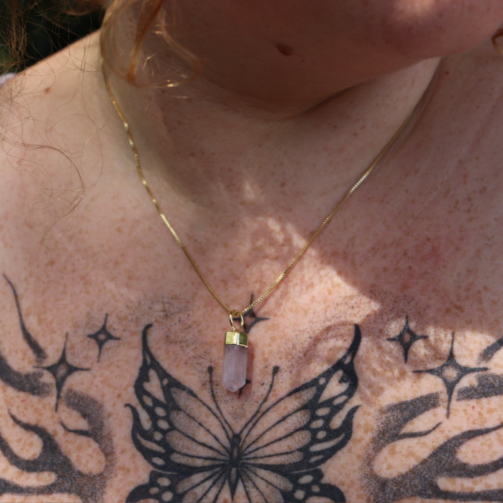 A woman wearing the Mini Rose Quartz Crystal Pendulum Necklace.