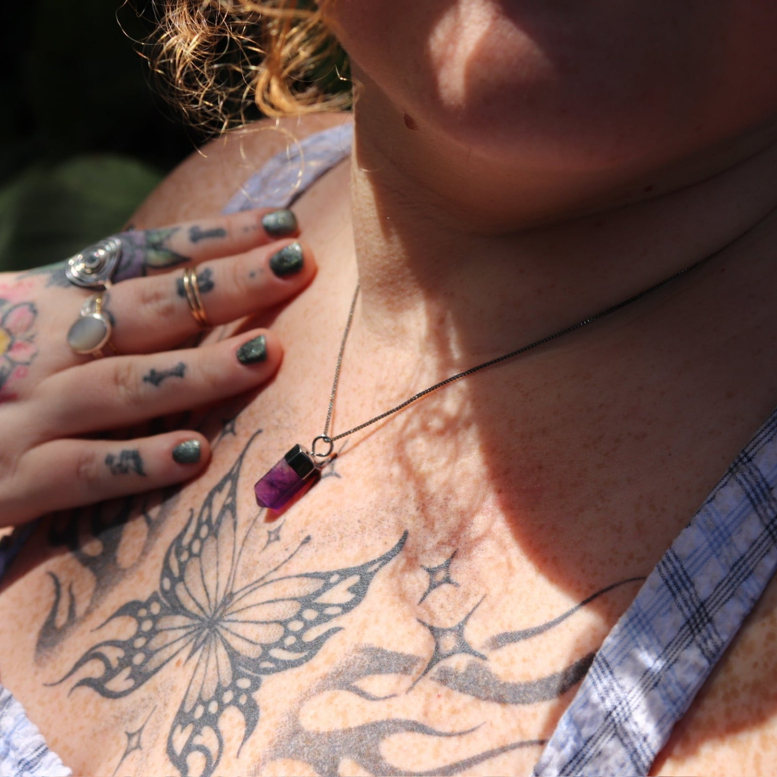Someone wearing the Mini Amethyst Crystal Pendulum Necklace.