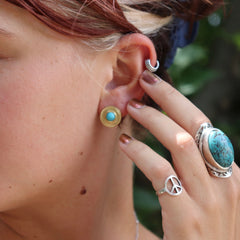 Someone wearing the Turquoise Gold Stud Earrings.