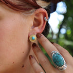 Someone wearing the Turquoise Gold Stud Earrings.
