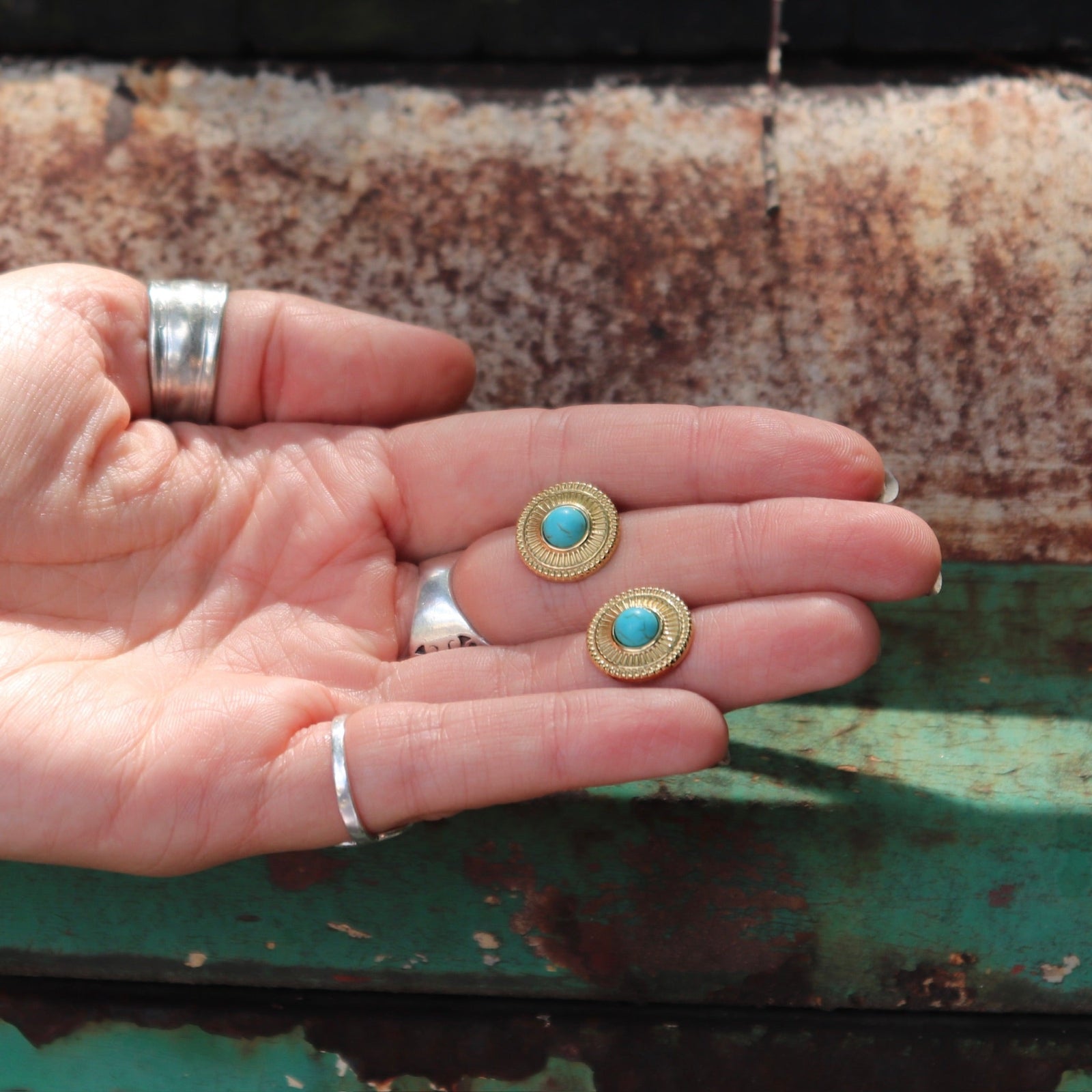 Someone holding the Turquoise Gold Stud Earrings.