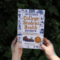 Someone holding the Ultimate College Student Health Handbook by Jill Grimes in front of greenery.