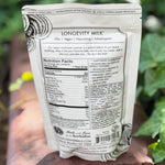 The back of the 7 Mushrooms Mocha Milk - Longevity Milk on a dusty red surface surrounded by ivy.