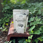 The 7 Mushrooms Mocha Milk - Longevity Milk on a dusty red surface surrounded by ivy.