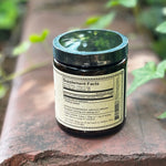 The back of the Blue Lotus Flower of Intuition Powder on a rusty red surface surrounded by ivy.
