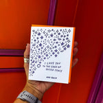 Someone holding the Outer Space I Love You Letterpress Greeting Card in front of an orange and pink wall.