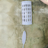 An up-close image of someone holding the Lavender Mist Bamboo Aloha Wind Chime in front of a concrete wall.
