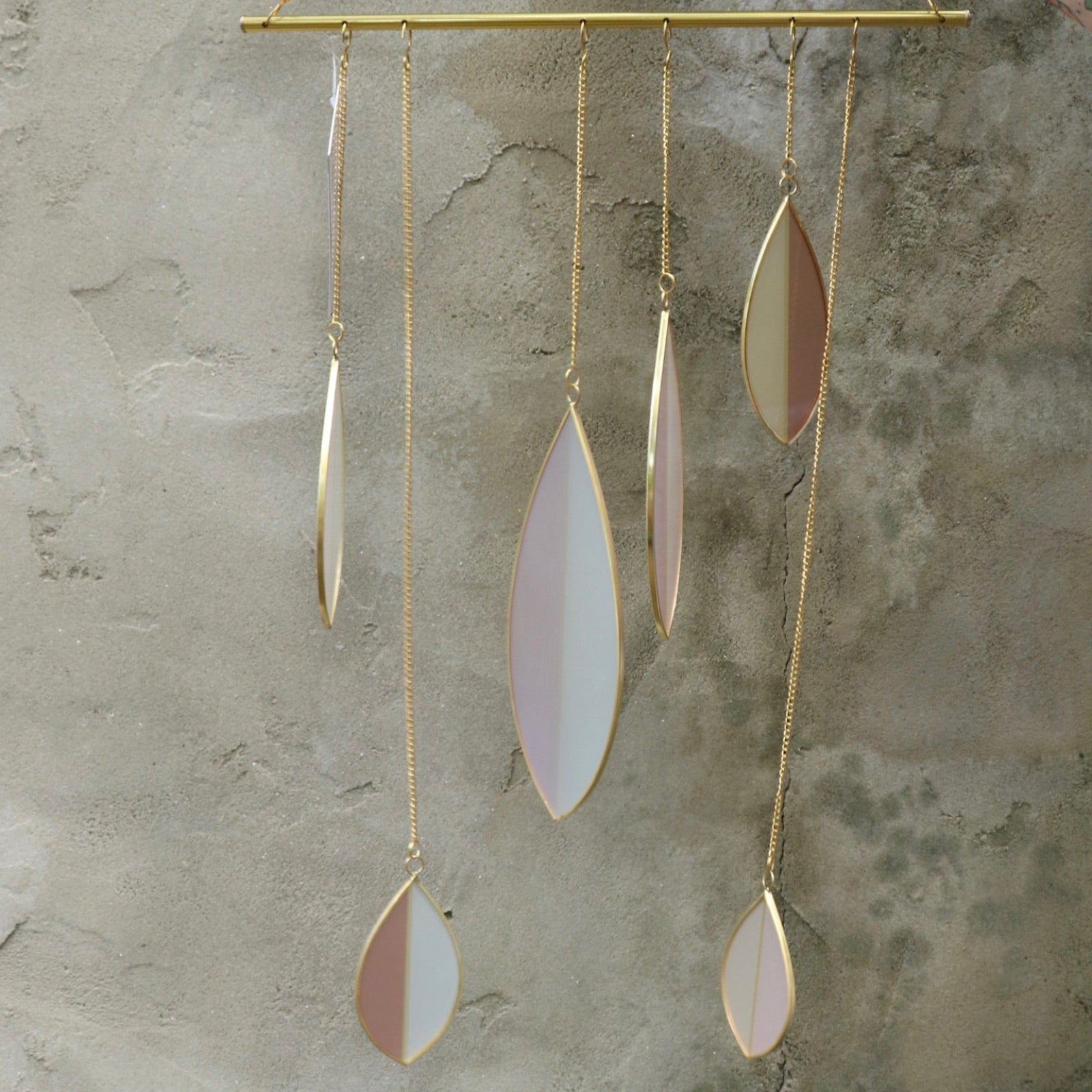 Someone holding the Mellow Stained Glass Suncatcher in front of a cement wall.
