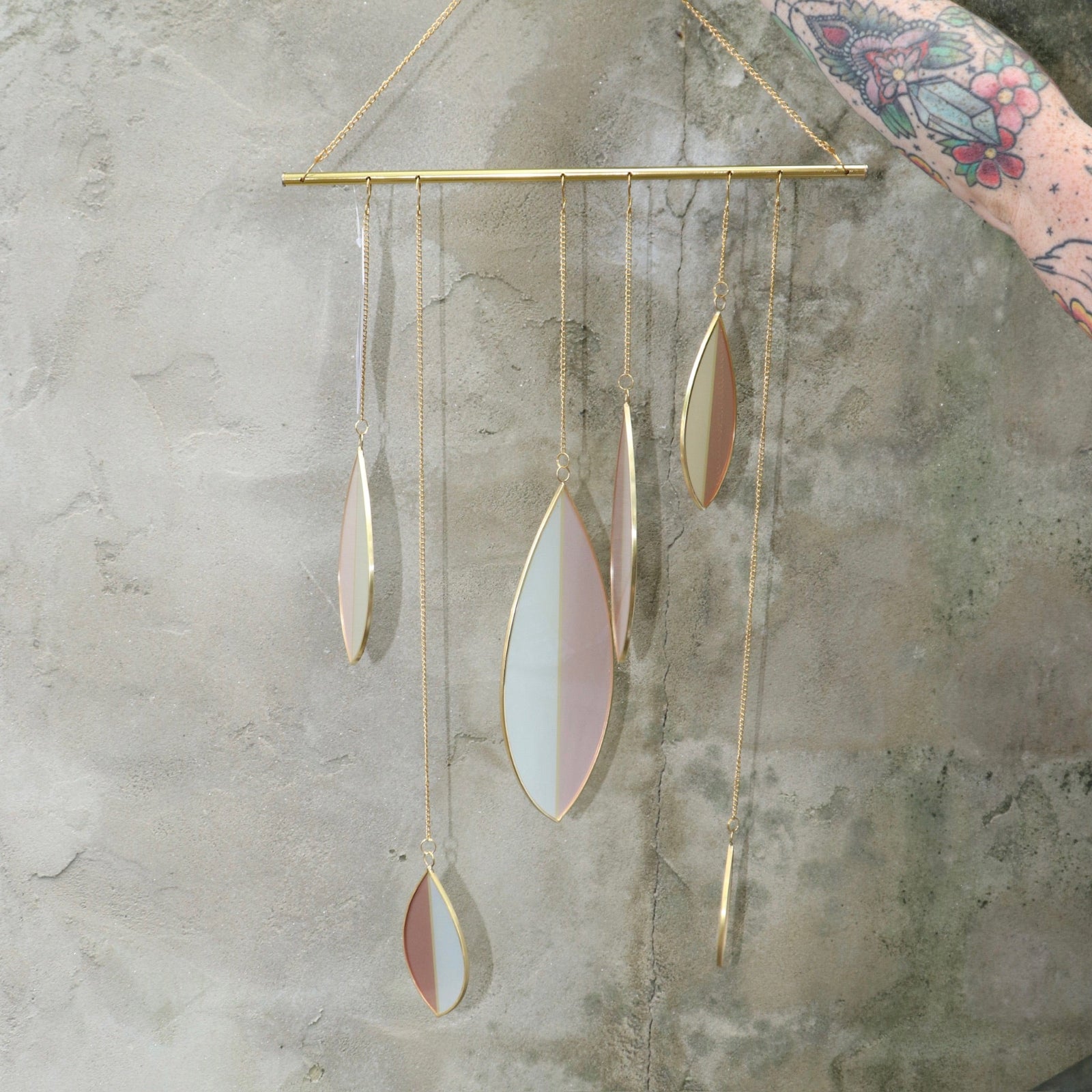 Someone holding the Mellow Stained Glass Suncatcher in front of a cement wall.
