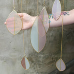 An up-close image of someone holding the Mellow Stained Glass Suncatcher in front of a cement wall.
