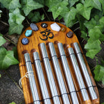 The Woodstock Zenergy Chakra Chime on a cement background with ivy surrounding it.