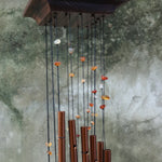 Someone holding the Amber Mystic Spiral Woodstock Wind Chime in front of a concrete wall.